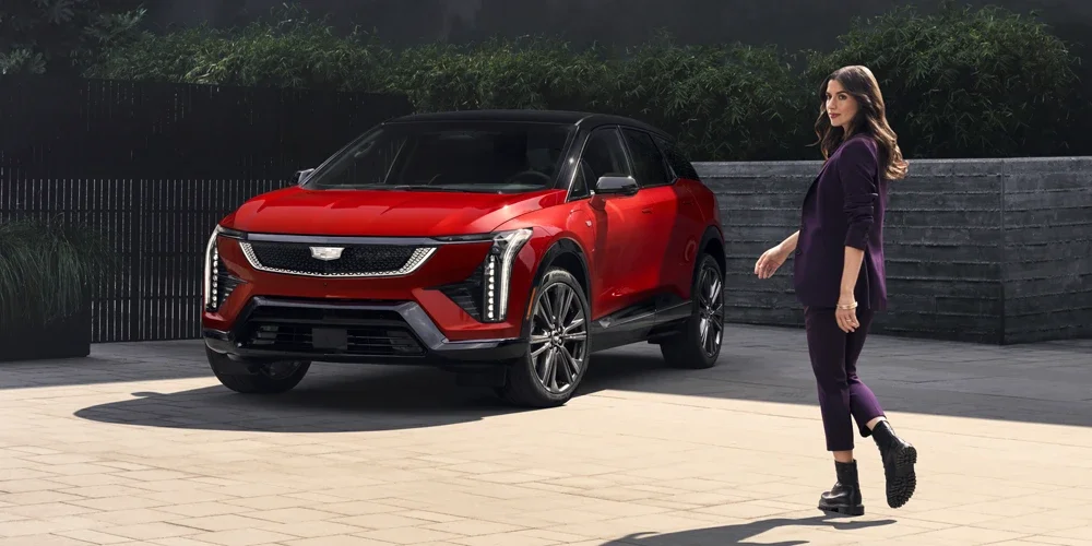 A Fashionably Dressed Woman Walking Towards a Parked Red Cadillac OPTIQ