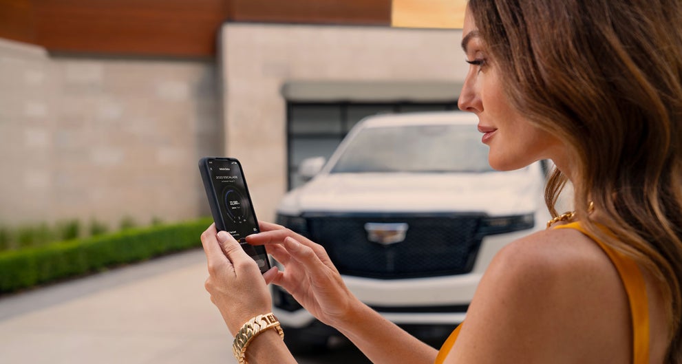 lady checking her mobile with a Cadillac vehicle background | CadillacDemo1 in Derwood MD